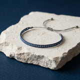 Thin navy woven bracelet with subtle pattern and adjustable cord